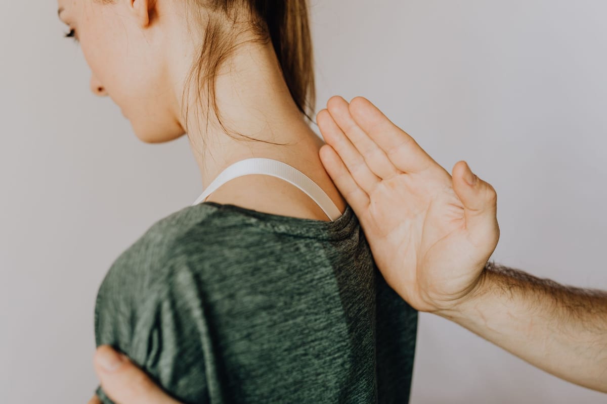 A practitioner checking a patient's back in a clinic treatment room