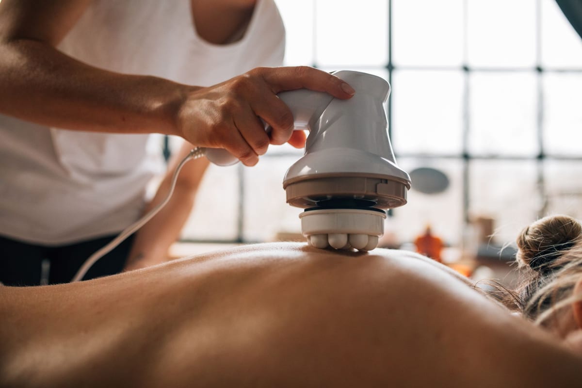 A handheld therapy device being worked across a patient's back