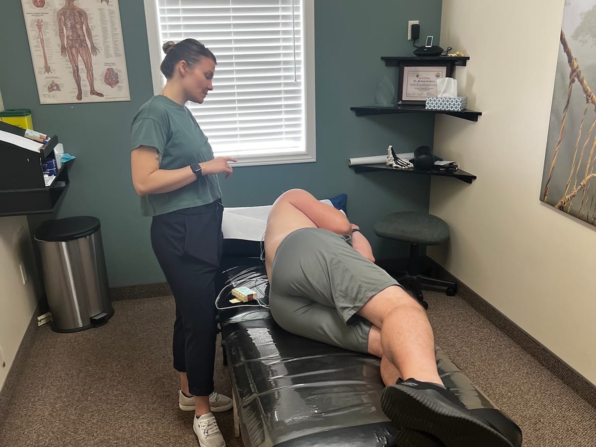 A therapist at the clinic beside a patient on the treatment table